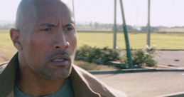 Dwayne Johnson in a tense moment from San Andreas, showcasing intense expression against a dramatic landscape backdrop.