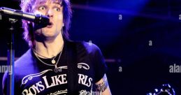 Martin Johnson from Boys Like Girls performing passionately on stage, guitar in hand, wearing a branded t-shirt.