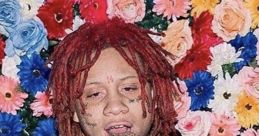 Trippie Redd in a floral backdrop, wearing a graphic hoodie and silver chains, showcasing his unique style.