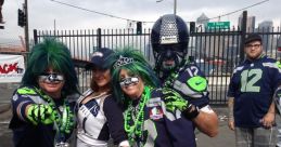 Fans dressed in Seattle Seahawks gear pose playfully, showcasing vibrant colors and passionate crowd noise atmosphere.