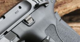 Close-up of M&P M2.0 handgun showcasing grip and trigger, set against a rustic wooden background.