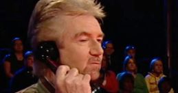 Host on the set of Deal Or No Deal UK, engaged in a phone call while contestants and audience watch intently.