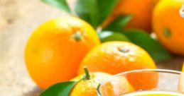 Freshly squeezed Orangensaft in a glass next to ripe oranges and green leaves on a rustic wooden table.