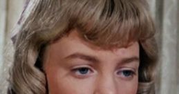 Close-up of Nellie Oleson, portrayed by Alison Arngrim, showcasing her distinct hairstyle and expression in a vintage scene.