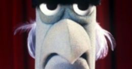 Sam the Eagle, created by Frank Oz, displays a stern expression against a red curtain backdrop.