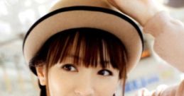 Yui Horie smiling playfully, wearing a stylish hat and a cute, patterned sweater in a light-filled environment.