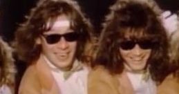 Van Halen's "Hot For Teacher" video features energetic performers in sunglasses and beige coats, capturing the playful spirit.