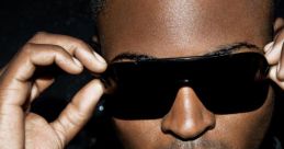 Taio Cruz poses confidently in sunglasses, promoting his hit song "Dynamite" from the international version.