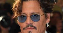 Johnny Depp wearing sunglasses and a stylish suit, showcasing his iconic look at a red carpet event.