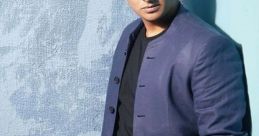 Jiiva in a stylish blue jacket and black t-shirt, posing confidently against a textured backdrop.