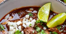 Savory beef stew topped with onions, cilantro, lime wedges, and pink pickled onions, perfect for a hearty meal.