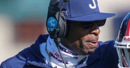 Coach discussing strategy in a Big Twelve Conference football game, wearing headphones and team apparel.