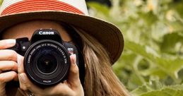 Young woman with a Canon camera in a green garden, capturing nature with a stylish hat and patterned blouse.