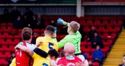 Kidderminster Harriers players compete for a high ball during an intense football match at Aggborough Stadium.