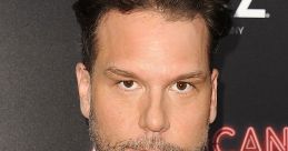 A poised Dane Cook in a black suit, showcasing his signature style at a glamorous red carpet event.