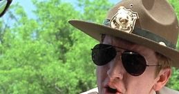 Close-up of a state trooper in shades, iconic scene from Super Troopers showcasing comedic law enforcement antics.