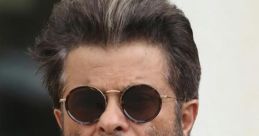 Anil Kapoor sporting sunglasses and a stylish beard, exuding charm and sophistication in a casual outfit.