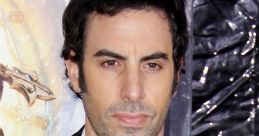 Actor at a premiere event, known for the character Borat, showcasing a suave look in a black suit and white shirt.