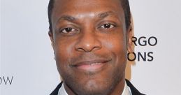 Chris Tucker smiles confidently in a formal suit, showcasing his charismatic personality and style at a public event.