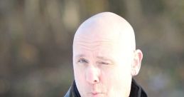 Frank Cotolo making a playful expression outdoors, wearing a leather jacket and scarf, set against a blurred natural background.