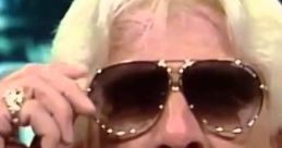 Rick Flair, wearing sunglasses, passionately speaking with excitement, embodies the essence of wrestling charisma.