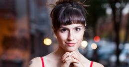 Young woman in a red dress poses thoughtfully outdoors in an urban setting, capturing a moment of elegance and charm.