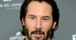 Keanu Reeves at a promotional event, showcasing his iconic look as John Wick, with a stylish dark suit and beard.