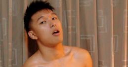 Shirtless small Asian boy posing confidently in front of curtains, showcasing a fit physique and playful expression.