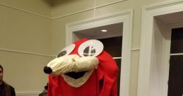 Red character costume referencing "De Way," featuring large expressive eyes and playful design in a convention setting.