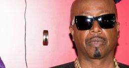 MC Hammer poses confidently in a stylish black outfit with gold chains, showcasing his iconic hip-hop style.