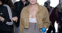 Demi Lovato stylishly arrives at the airport, showcasing her trendy look amidst a crowd. Prank Call: Tom Cruise vibes.