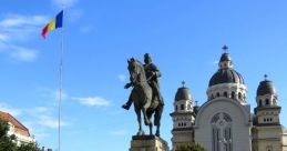 Statue of a rider on horseback in Targu, with the Romanian flag and a historic building in the background.