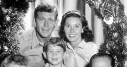 Cast of the Andy Griffith Show poses cheerfully around a festive Christmas wreath, showcasing holiday spirit and joy.