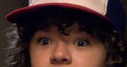 Dustin from Stranger Things shows an excited expression while wearing a red and white cap, showcasing his signature style.