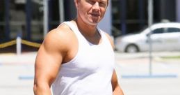 Mark Wahlberg in a white tank top and patterned pants, showcasing his muscular build in a casual outdoor setting.