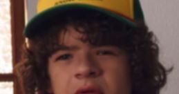 Dustin Henderson wearing a yellow camp hat and orange T-shirt, showcasing his signature quirky style in "Stranger Things.