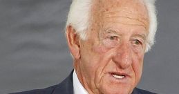 Bob Uecker speaking at an event, wearing a suit and striped tie, highlighting his achievements and sports legacy.