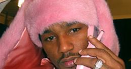 Cam'ron in a striking pink fur coat, holding a pink phone, showcasing his iconic style and flair in hip-hop fashion.