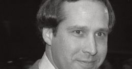 Chevy Chase smiling while wearing a suit and tie, surrounded by fans and media in a black-and-white scene.