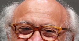 Danny DeVito smiling with glasses, showcasing his iconic look at a public event. Celebrated actor and filmmaker.