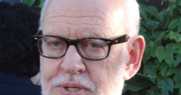 Frank Oz speaking at an event, wearing a suit and glasses, promoting his work in film and puppetry.