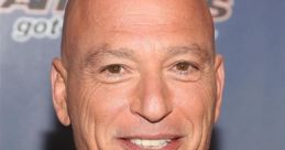 Howie Mandel smiles at a red carpet event, showcasing his signature bald head and engaging personality.