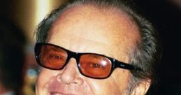 Jack Nicholson smiling broadly, wearing sunglasses and a tuxedo, with colorful ribbons at a prestigious event.