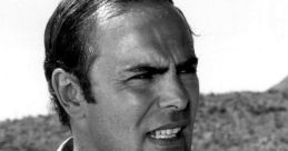 John Saxon in a dramatic pose, showcasing his intense expression, with a nature backdrop highlighting his acting charisma.