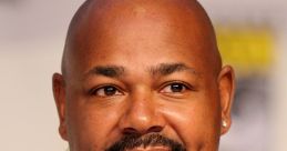 Kevin Michael Richardson speaking at a panel, showcasing his vibrant shirt and distinctive charisma at a popular convention.