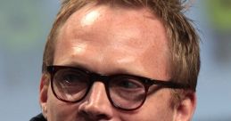 Paul Bettany smiling at a panel discussion, wearing glasses and a denim jacket, showcasing his engaging personality.