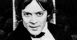 Raul Julia in a classic black and white portrait, exuding charm and charisma in formal attire.