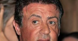 Sylvester Stallone at an event, wearing a stylish gray suit and tie, showcasing his iconic Hollywood presence.