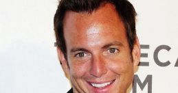 Will Arnett smiling and pointing directly at the camera, dressed in a black blazer and white shirt at a film festival event.