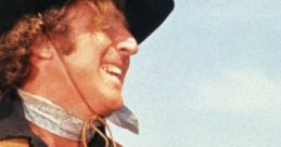 Smiling cowboy character on horseback from Blazing Saddles (1974) against a clear blue sky, capturing Western comedy essence.